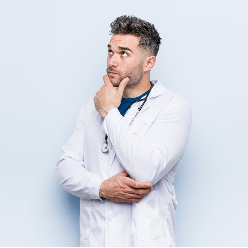 Young handsome doctor man looking sideways with doubtful and skeptical expression.